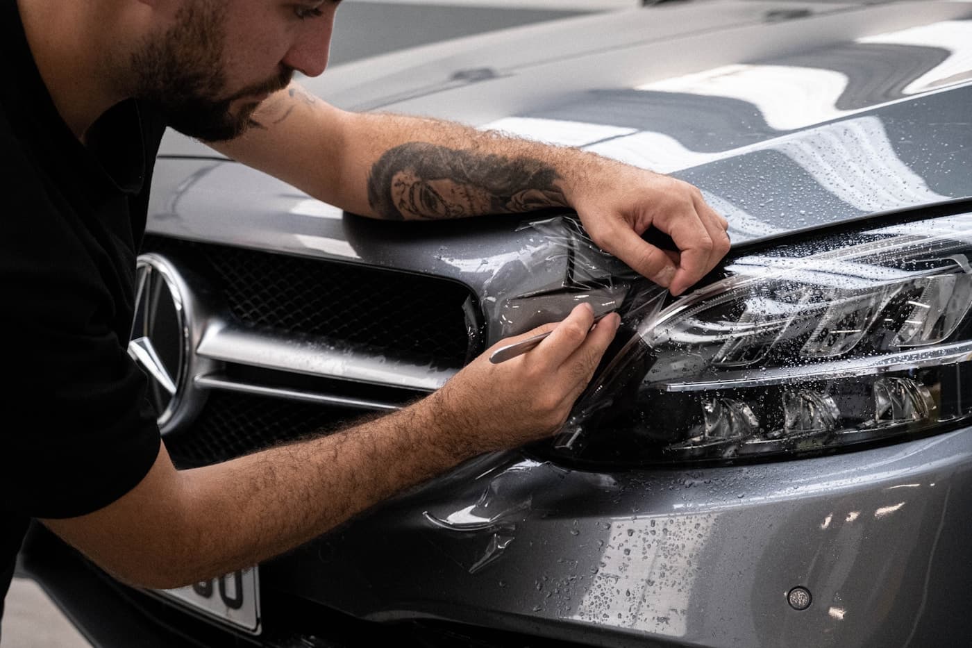 Professional detailer applying paint protection film on a vehicle